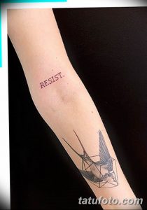 Фото тату птицы, выполненной из геометрических линий, и надписи 'RESIST' на предплечье. Современный и стильный рисунок татуировки.