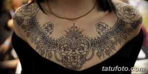 Фото тату сложного узора в стиле мехенди на груди и плечах. Детализированный рисунок татуировки, напоминающий кружево.