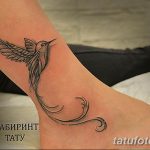 Фото тату на лодыжке: изящная колибри в полете с длинным изогнутым хвостом. Детализированный и воздушный рисунок.