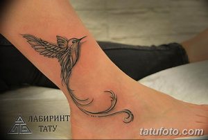Фото тату на лодыжке: изящная колибри в полете с длинным изогнутым хвостом. Детализированный и воздушный рисунок.