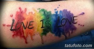 Фото тату с надписью 'Love is Love', выполненной в виде радужных брызг краски на руке. Яркий и красочный символ любви и равенства.
