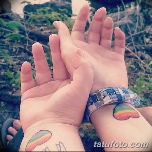 Фото тату: два радужных сердца на запястьях двух людей, символизирующие любовь и единство.