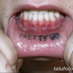 Фото тату: надпись 'PRETTY GAY' черными чернилами на внутренней стороне губы. Необычное и провокационное решение для самовыражения.