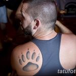Фото тату: реалистичный отпечаток лапы медведя на плече, выполненный в серых тонах.