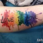 Фото тату: акварельная радуга с надписью 'Love is Love' на руке, выполненная в ярких и размытых цветах.