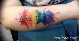 Фото тату: акварельная радуга с надписью 'Love is Love' на руке, выполненная в ярких и размытых цветах.