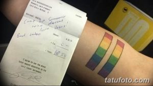 Фото тату: изображение чека с надписью 'Can't help someone who doesn't love Jesus. Bad tattoo' и две радужные полосы на руке.