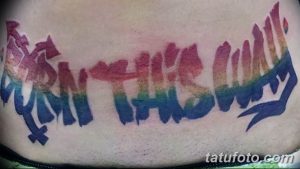 Фото тату на животе: надпись 'Born This Way' в цветах радуги, символизирующая принятие себя и гордость. Смелый и вдохновляющий рисунок татуировки.