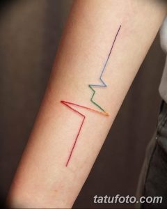 Фото тату на предплечье, изображающее кардиограмму, линии которой окрашены в цвета радуги. Оригинальный и символичный рисунок.