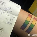 Фото тату на предплечье, сочетающее в себе изображение чека с надписью и две полосы радуги. Оригинальный и запоминающийся рисунок.