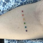 Фото минималистичного тату в виде точек, расположенных в цветах радуги на руке. Нежный и символичный рисунок.