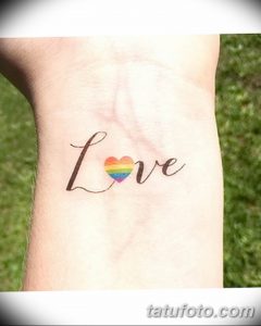 Фото тату надписи "Love" с радужным сердцем вместо буквы "o". Нежный и символичный рисунок на запястье.