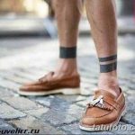 Фото тату: две черные полосы, татуированные на лодыжках мужчины. Минималистичный и стильный дизайн для повседневной носки.