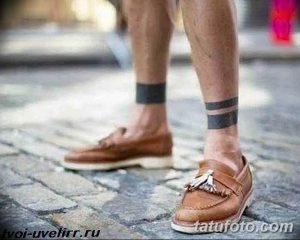 Фото тату: две черные полосы, татуированные на лодыжках мужчины. Минималистичный и стильный дизайн для повседневной носки.