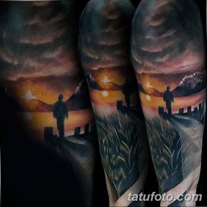 Фото тату: реалистичный пейзаж заката с одинокой фигурой человека, татуировка на рукаве, теплые тона, драматичный сюжет.