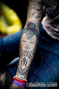 Фото татуировки Будды на предплечье, выполненной в стиле графика с использованием черных линий и теней.