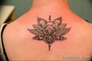 Фото тату на лопатке: стилизованный цветок лотоса, выполненный в технике blackwork. Детализированный рисунок с тонкими линиями и точками.