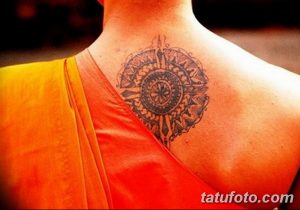 Фото татуировки с изображением сложного кругового узора на спине человека. Рисунок выполнен в черном цвете с использованием тонких линий и геометрических форм.