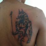 Фото татуировки Анубиса на спине. Рисунок выполнен в минималистичном стиле с использованием черно-серых оттенков.