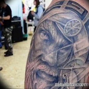 Фото тату головы волка с часами на фоне, расположенного на плече. Татуировка выполнена в черно-серых тонах с элементами сюрреализма и реализма.