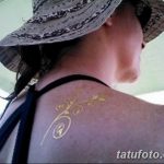 Фото тату: золотой узор в виде завитушек и листьев украшает плечо девушки, создавая изящный и элегантный боди-арт.
