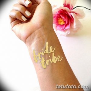 Фото тату: золотая надпись "bride tribe" украшает запястье девушки, создавая стильный и праздничный образ для свадебной вечеринки.