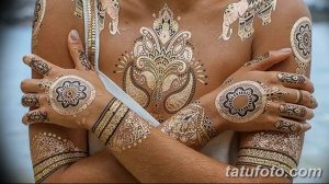 Фото тату хной: золотые узоры в индийском стиле на груди, руках и предплечьях девушки. Детализированный рисунок татуировки.