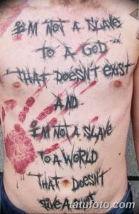 Фото тату на груди и животе с черной надписью 'I'M NOT A SLAVE...' и красными брызгами, имитирующими кровь. Смелый и вызывающий рисунок татуировки.