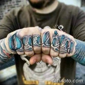Фото тату с надписью 'Quality' на костяшках пальцев. Рисунок выполнен в синих тонах с использованием теней и бликов.