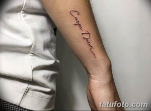 Фото тату надписи 'Carpe Diem' на предплечье. Изящный шрифт, минималистичный дизайн, вдохновляющий смысл. Идеально для любителей латыни и мотивационных татуировок.