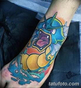 Фото тату на предплечье с изображением покемона Gyarados, извергающего пламя, в ярком и детализированном стиле.