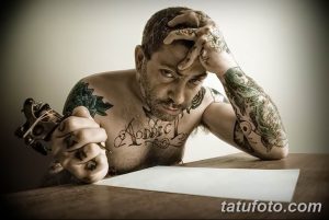 Фото тату мастера, делающего татуировку. Мужчина с татуировками на руках и груди, сосредоточенно работающий над рисунком.
