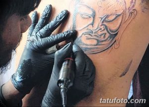 Фото процесса татуировки: тату-мастер наносит эскиз татуировки на плечо клиента. Видны руки мастера в перчатках и тату-машинка.