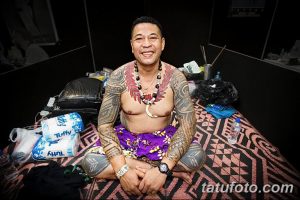 Фотография мужчины с традиционной полинезийской татуировкой, покрывающей большую часть его тела, демонстрирующая силу и красоту культуры.
