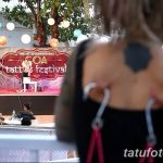 Фото с фестиваля татуировок в Гоа, демонстрирующее сцену и татуированную спину девушки. Яркое изображение, передающее дух свободы и творчества.