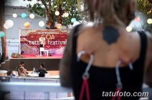 Фото с фестиваля татуировок в Гоа, демонстрирующее сцену и татуированную спину девушки. Яркое изображение, передающее дух свободы и творчества.