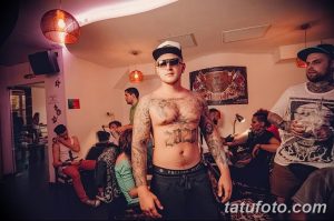 Фото тату на теле мужчины в тату-салоне, демонстрирующего обширные татуировки на груди, животе и руках. Яркий пример современного искусства на коже.