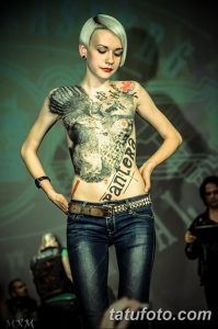 Фото тату: девушка демонстрирует татуировку на спине, изображающую стилизованный рисунок с надписью 'Pantera'.