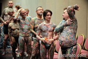 Фото тату: группа мужчин и женщин, чьи тела полностью покрыты яркими и детализированными татуировками, позируют на фестивале тату.