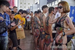 Фото тату: группа людей с традиционными японскими татуировками, демонстрирующими сложные узоры с изображением карпов кои, волн и цветов.