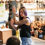Фото тату девушки с татуировкой в стиле маори на руке, демонстрирующей свою татуировку во время выступления на сцене.