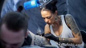 Фото тату процесса нанесения татуировки на ногу клиента. Видна рука мастера с тату-машинкой и нога клиента с начинающимся рисунком.