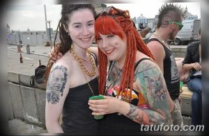 Фотография двух девушек с яркими татуировками на руках и теле на тату-фестивале.