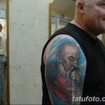 Фотография татуировки с изображением реалистичного портрета старца с длинной бородой на плече мужчины.