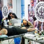 Фото процесса нанесения татуировки на ногу мужчины. Видна тату-машинка и рука мастера, работающего над рисунком.