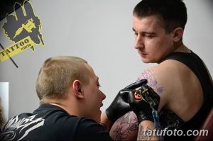 Фото тату процесса нанесения татуировки на плечо. Мастер переносит эскиз на кожу клиента.