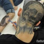 Фото тату реалистичного портрета волка на затылке мужчины. Детализированный рисунок татуировки выполнен в черно-серых тонах.