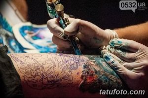 Фото процесса нанесения татуировки на руку. Мастер наносит контур и цвет, используя тату-машинку.