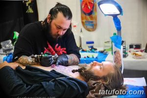 Фото процесса нанесения татуировки: мастер делает тату с изображением красного дракона на спине клиента.