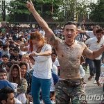 Фото тату: мужчина в экстазе танцует во время традиционного таиландского ритуала татуировки. Вокруг него толпа людей.